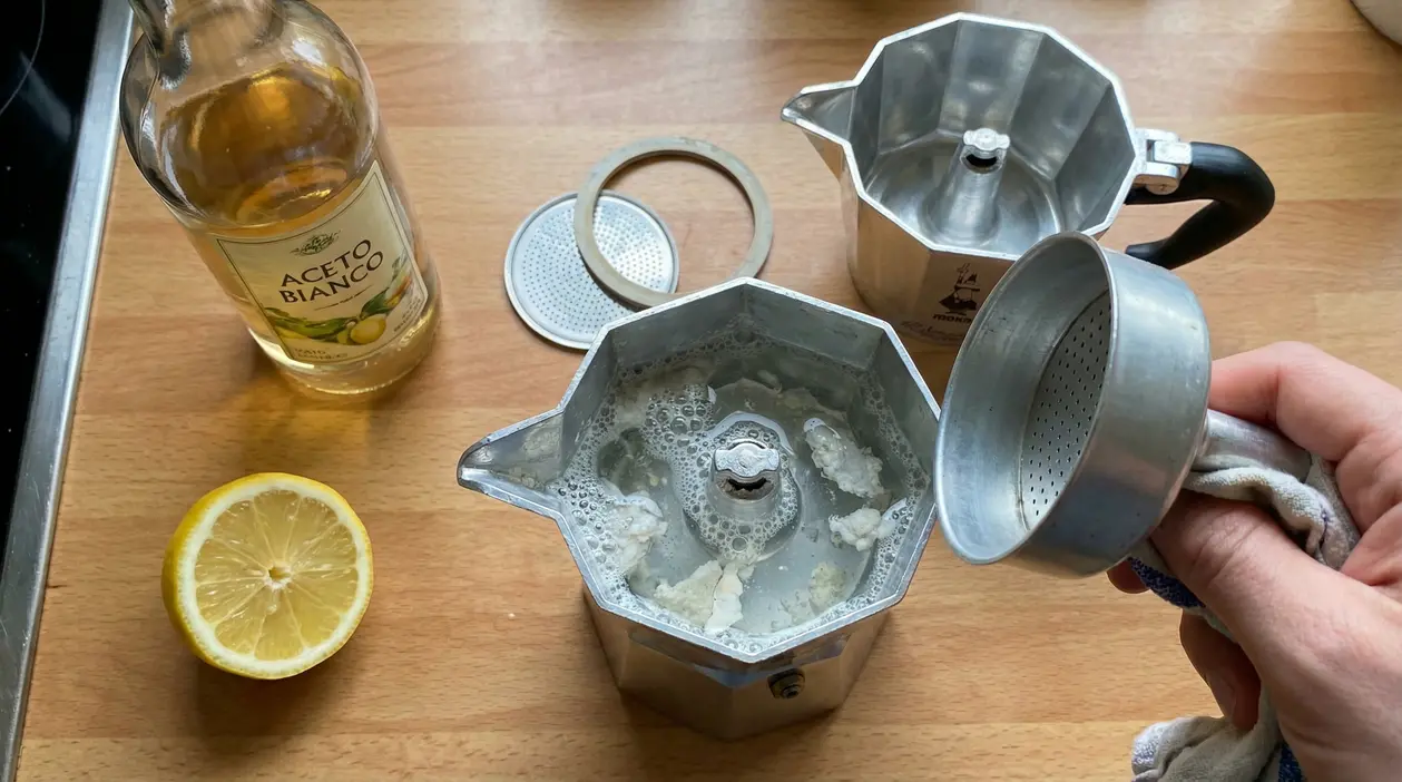 Moka smontata con calcare e acqua, accanto a aceto bianco e mezzo limone su piano cucina